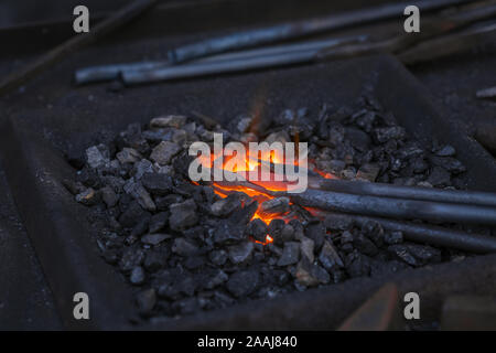 Der Schmied schmieden manuell das geschmolzene Metall auf dem Amboss in Schmiede mit Funken Feuerwerk Stockfoto