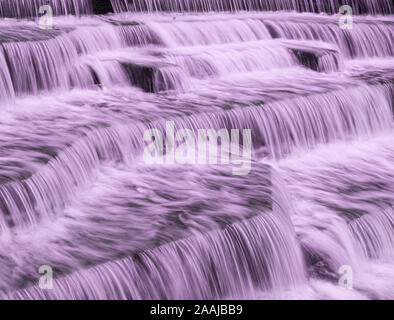 Wasser Kaskadierung über Wehr Schritte auf Canal Helling, blur unscharf Bewegungs- und freeze frame von Wassertröpfchen für Hintergrund tectures und Layer Effe Stockfoto