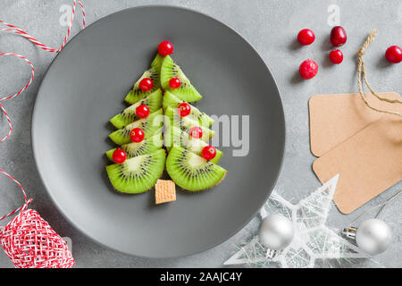 Kiwi Weihnachtsbaum mit Johannisbeeren, lustig Essen für Kinder. Weihnachten Lebensmittel Hintergrund. Stockfoto