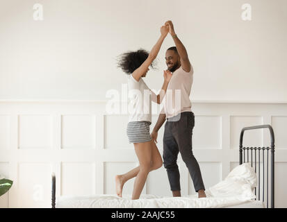 Gerne afrikanische amerikanische Paar tanzen auf dem Bett wirbelnden Stockfoto