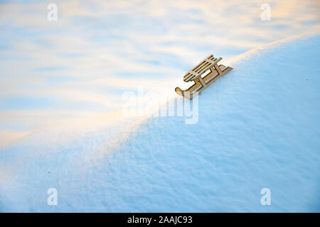 Schlitten auf dem Schnee für die Grußkarte. Holz Schlitten auf weißem Schnee. Spielzeug der Schlitten auf Snow Hill. Kopieren Sie Platz. Grußkarte für Winterurlaub. Symbol für das neue Jahr. Grußkarte, Broschüre. Hintergrund der Schnee Stockfoto