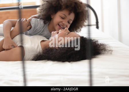 Happy biracial Mom haben sie Spaß, spielen Sie mit Tochter im Schlafzimmer Stockfoto