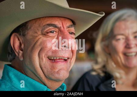 Lachender älterer Mann mit Cowboyhut bei einem Familienereignis Eine gute Zeit zu haben Stockfoto