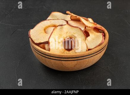 Apple Chips in eine hölzerne Schüssel auf einem dunklen Hintergrund Stockfoto