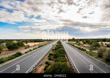 Spektakuläre Aussicht auf eine Autobahn in Mallorca genannt Autopista de Levante in Spanisch, mit einem eindrucksvollen Himmel und einem gut definierten Horizont Stockfoto