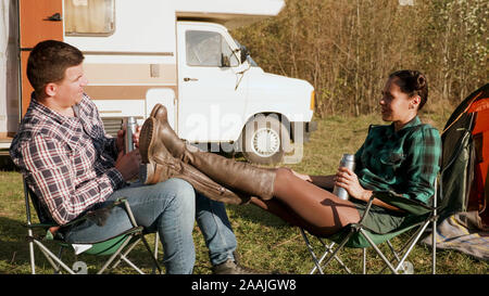 Kaukasische copuple zusammen Entspannen auf Camping Stühle vor Ihrer retro Wohnmobil. Stockfoto