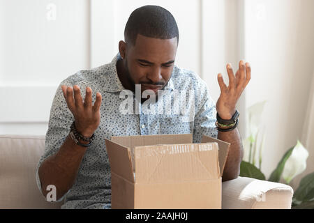 Biracial männlichen Paket öffnen falsche Reihenfolge erhalten konfus Stockfoto