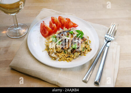 Low carb diet Meal, Risotto von Blumenkohl mit getrockneten Steinpilzen, mit Petersilie und Parmesan auf einer Platte auf einer hölzernen Tabl garniert Stockfoto