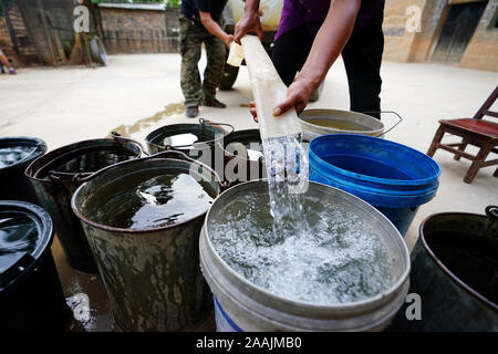 (191122) - YICHENG COUNTY, November 22, 2019 (Xinhua) -- arbeiten Mitarbeiter helfen, Wasser zu einem Dorfbewohner in Nanling Dorf Yicheng County verteilen, im Norden der chinesischen Provinz Shanxi, 3. Juli 2019. Da der Schalter gezogen wurde, das Wasser spritzte aus 403 Meter in Down Under. Nanling's Village sehr zuerst tief - Wasser gut ging, in einem frühen Wintermorgen. In der Vergangenheit, das Dorf, über die Schluchten des Zhongtiao Berge im Norden Chinas verbreiten, hatte allein auf Mud-pits stützte seine wertvollen Trinkwasser für Jahrhunderte zu speichern. Durch die Angst vor der Dürre heimgesucht, die Generationen hatte der direkten geträumt Stockfoto