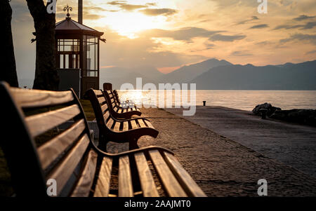 Gardasee, Italien. Einen ruhigen Blick auf den Sonnenuntergang von Bänken, die über den Gardasee, Italien, gegenüber der italienischen Alpen. Stockfoto