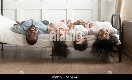 Afrikanische Familie liegt auf dem Bett Köpfe unten an der Kamera auf der Suche Stockfoto