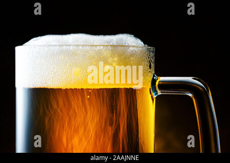 Licht Bierkrug mit weißer Schaum auf dunklem Hintergrund Nahaufnahme Stockfoto