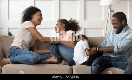 Happy afrikanischen Familie kitzelt kleine Kinder Spaß zu Hause in Stockfoto