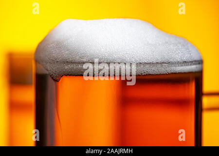Licht Bierkrug mit weißer Schaum auf gelbem Hintergrund Nahaufnahme Stockfoto