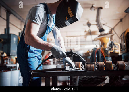 Portrait einer jungen Arbeitnehmer in einem großen metallverarbeitenden Betrieb. Der schweisser Techniker arbeitet in einer Atemschutzmaske Stockfoto