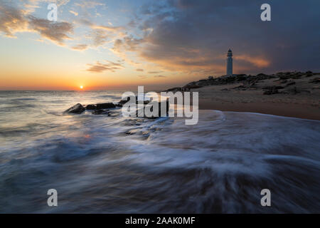 Kap Trafalgar Leuchtturm bei Sonnenuntergang mit Wellen am Strand brechen, Los Caños de Meca, Costa de la Luz, Provinz Cadiz, Andalusien, Spanien, Europa Stockfoto