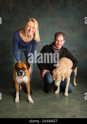 Studio Portrait von Paar mit Boxer und Golden Retriever Lab mix Stockfoto