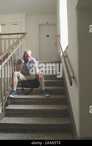 Junger Mann wartet im Stiegenhaus - Junger Mann im Treppenhaus warten Stockfoto