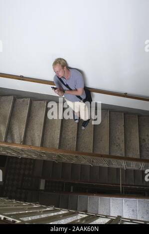 Junger Mann telefoniert im Stiegenhaus - Junger Mann mit Handy auf Treppe Stockfoto