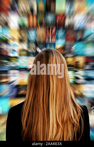 Junge blonde Frau an einem Bildschirm mit Bildern, Konzept für Streaming Media und Social Media suchen Stockfoto