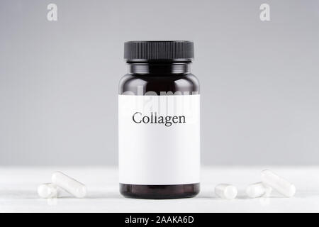 Nahrungsergänzung collagen Flasche und Kapseln auf Grau Stockfoto