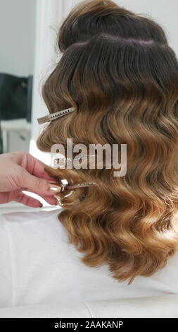Friseurhands, die Klammern in die Haare eines Kunden legen. Stockfoto