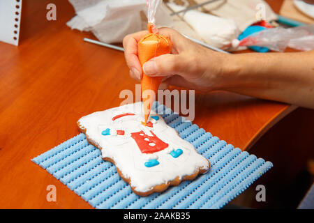 Ein junges Mädchen ist in Dekoration Lebkuchen Cookies eingeschaltet. Weihnachten und Neujahr Geschenke und die Herstellung von Lebkuchen Kekse für Weihnachten Stockfoto