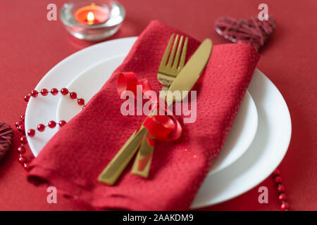 Serviertisch mit Gabel, Messer, Serviette und Herzen Dekoration für Valentinstag. Tisch in roten Farben am Valentines Tag. Ansicht von oben. Stockfoto