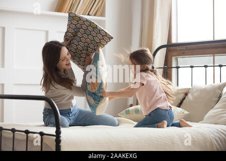 Verspielte Mutter und Tochter spielen in Kissenschlacht Stockfoto