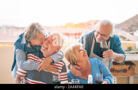 Happy Senioren paar Spaß zusammen speisen auf der Terrasse - Romantische ältere Menschen trinken Wein und genießen Sie einen sonnigen Tag auf der Dachterrasse Stockfoto