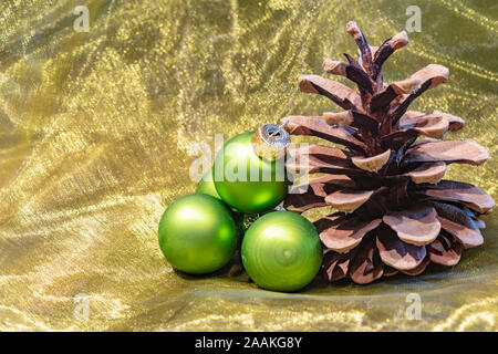 A Pine Cone und grünen Weihnachtsbaum Kugeln auf einem farbigen Tuch. Stockfoto
