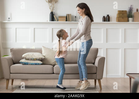 Glückliche junge Mutter und Tochter gemeinsam Spaß haben tanzen Stockfoto