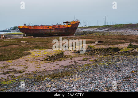 Ein rostiges Schiffswrack im Schlamm der Walney Kanal, von der Straße auf Roa Island, Cumbria, England, UK gesehen Stockfoto