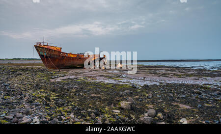 Ein rostiges Schiffswrack im Schlamm der Walney Kanal, von der Straße auf Roa Island, Cumbria, England, UK gesehen Stockfoto