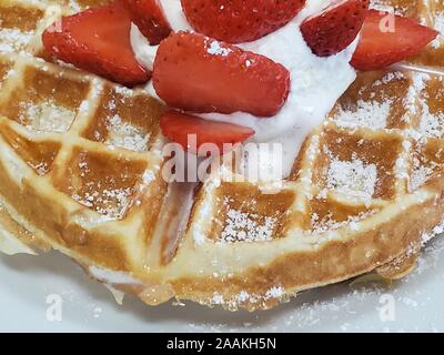 Nahaufnahme der belgische Waffel mit in Scheiben geschnittenen Erdbeeren und Schlagsahne auf weiße Platte, 2. November 2019. () Stockfoto