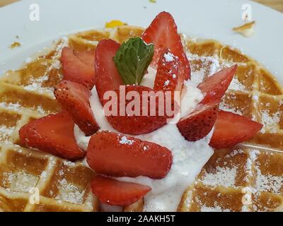 Nahaufnahme der belgische Waffel mit in Scheiben geschnittenen Erdbeeren und Schlagsahne auf weiße Platte, 2. November 2019. () Stockfoto