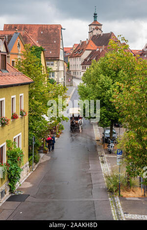 Während eines regnerischen Sommertages а Pferdekutsche, die Touristen durch die mittelalterliche Stadt Rothenburg ob der Tauber, Franken, Bayern führt. Stockfoto