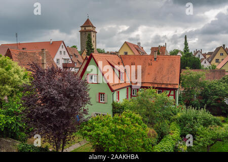 Schönes altes grünes Haus unter grünen Bäumen, Dächer mittelalterliche Stadt Rothenburg ob der Tauber im Hintergrund, Bayern, Deutschland. Stockfoto