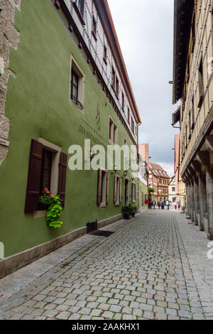 Eine schmale, gepflasterte Straße mit einem Hotel in einem alten traditionellen Haus und einer Gruppe von Touristen in einer der am besten erhaltenen mittelalterlichen Städte Deutschlands. Stockfoto