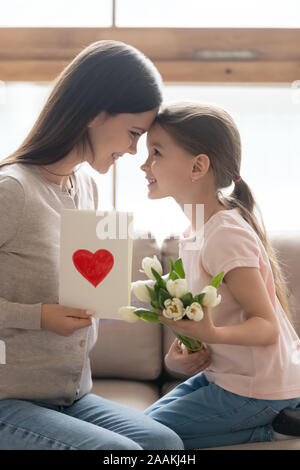 Preschooler Kind vorhanden Blumen und Postkarte an junge Mamma Stockfoto