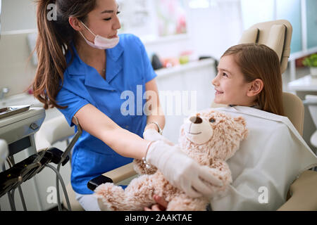 Zahnmedizinische Klinik. Wenig lächelnde Mädchen sitts in der Zahnarztpraxis. Stockfoto