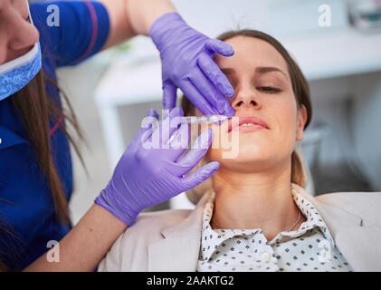 Junge Frauen, die kosmetische Injektion auf ihren Lippen. kosmetische Verfahren mit Spritze Stockfoto