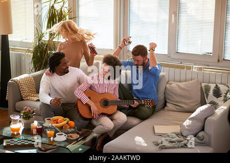 Zwei Paare genießen mit Musik und Getränken im Wohnzimmer Stockfoto