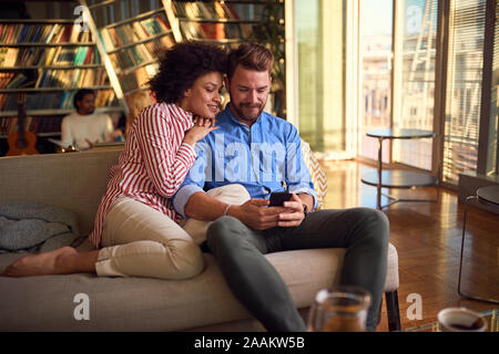 Schönes junges Paar, das Spaß zusammen mit einem Smartphone Stockfoto