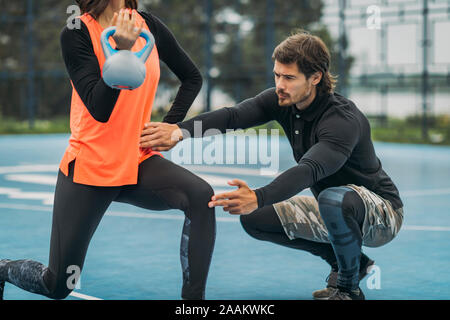 Junge sportliche Frau heben kettlebell, Arbeiten mit Personal Fitness Trainer. Stockfoto
