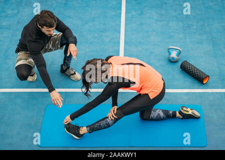 Passen junge Frau, Dehnen nach dem Training mit Personal Fitness Trainer. Stockfoto