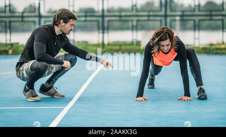Junge sportliche Frau Training im Freien mit Personal Fitness Trainer. Stockfoto