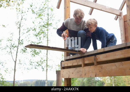 Vater und Sohn bauen Baumhaus im Garten Stockfoto