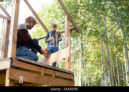 Vater und Sohn bauen Baumhaus im Garten Stockfoto