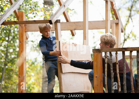 Vater und Sohn bauen Baumhaus im Garten Stockfoto